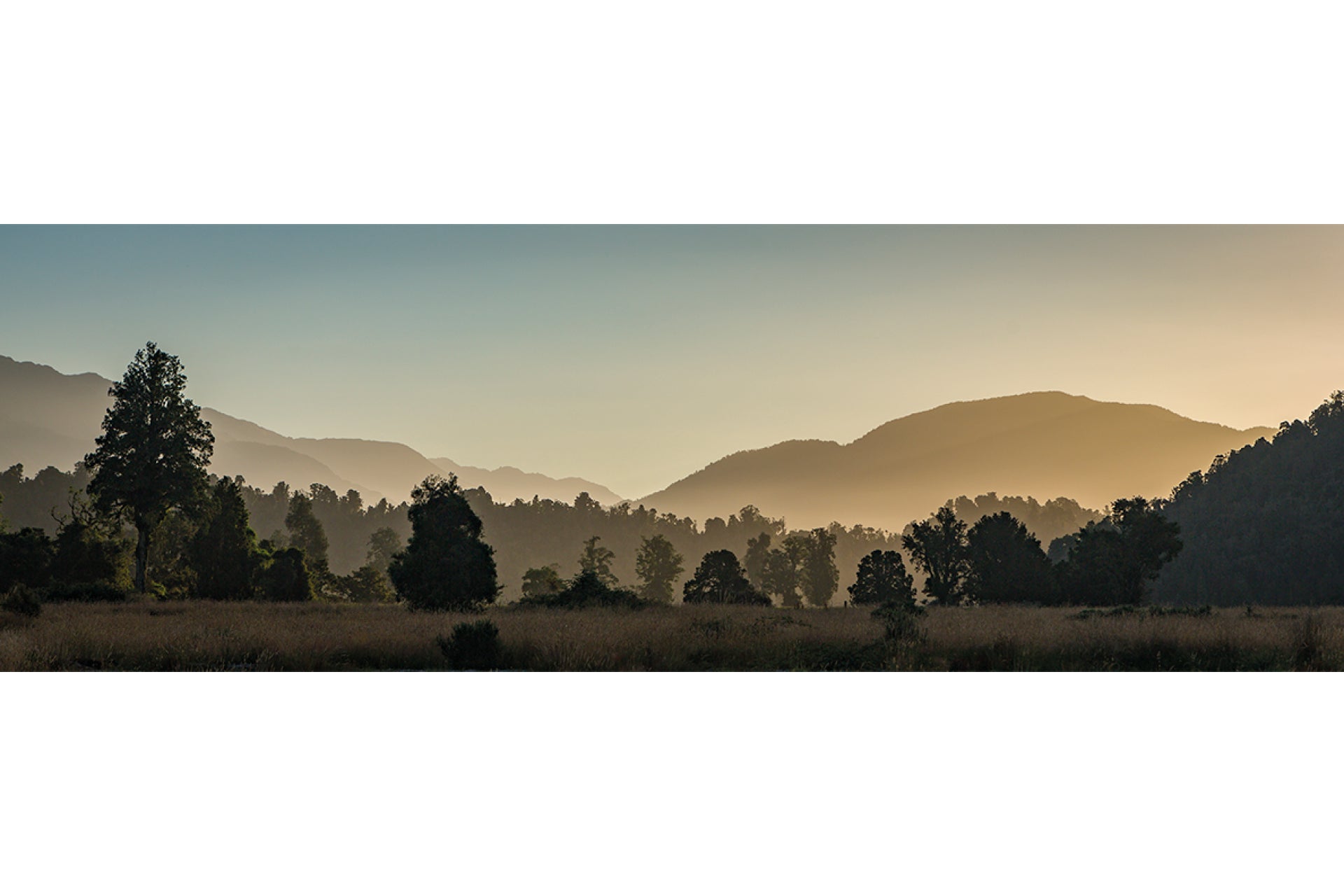 Tranquil dusk on West Coast New Zealand Southern Alps, with golden hues fading over majestic peaks and serene horizons in Westland