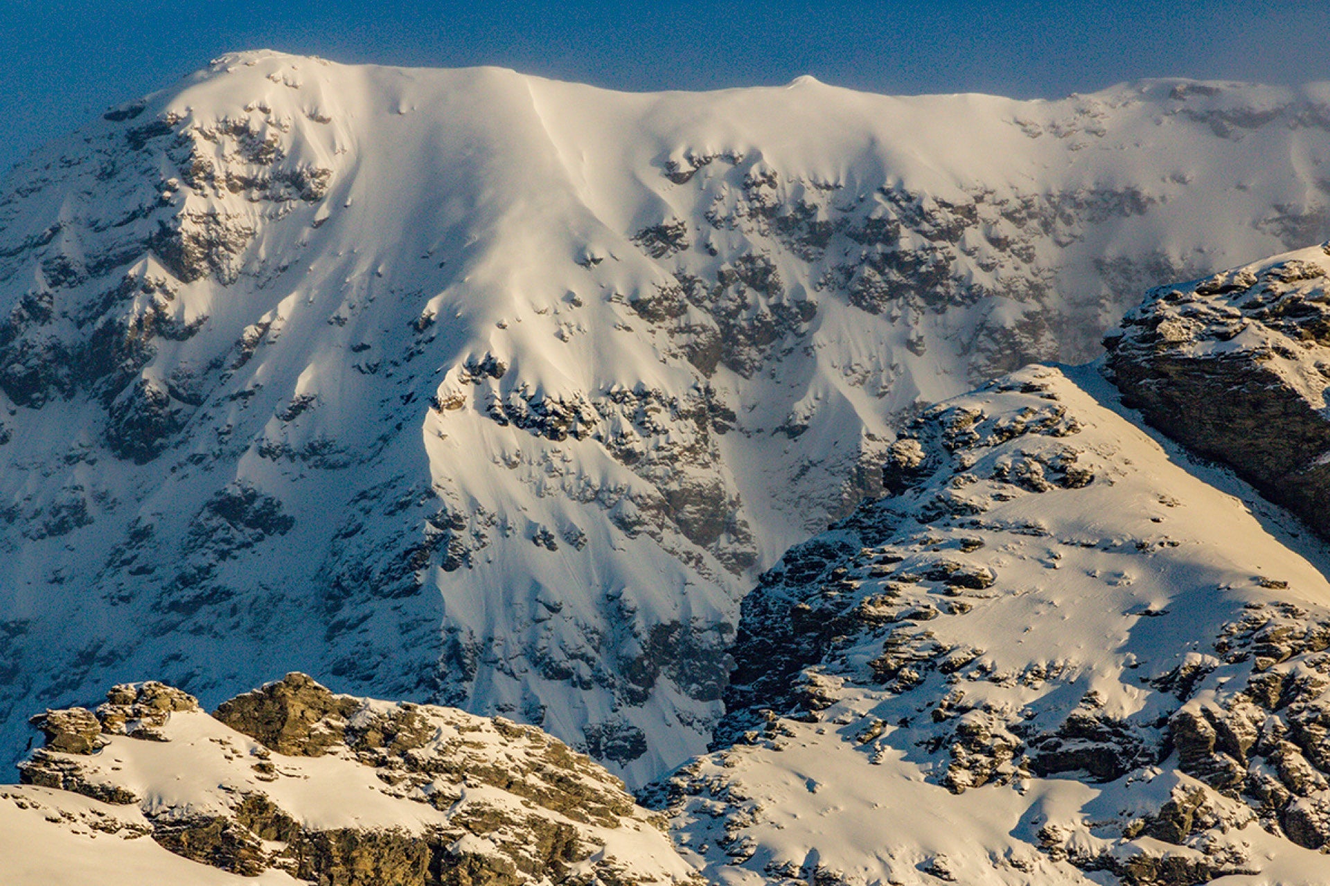 Freshly snow-plastered Mount Earnslaw (Pikirakatahi) in Glenorchy New Zealand, viewed from unique high vantage over Rees Valley with towering peaks and Otago wilderness.