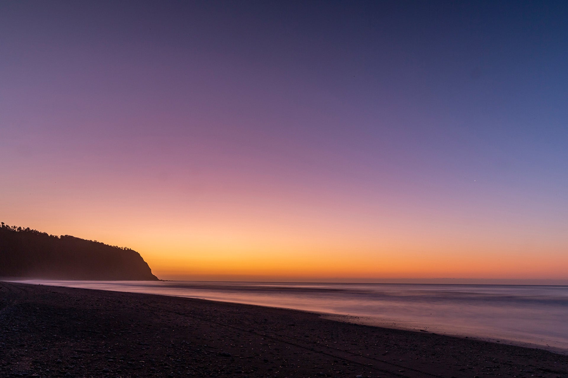 Tranquil ocean at Okarito on New Zealand's West Coast in peaceful repose as twilight fades via long exposure, a moment of calm amid wild shores, captured by photographer Steve Couper – ideal for coastal dreamers seeking Aotearoa's gentle beauty.